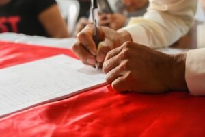 Manos firmando contrato para contratar trabajadores de Perú y Chile en España, proceso asesorado por DEI Abogacía