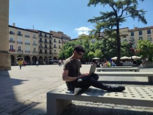 Nómada digital peruano trabajando con laptop en plaza española, caso gestionado por DEI Abogacía
